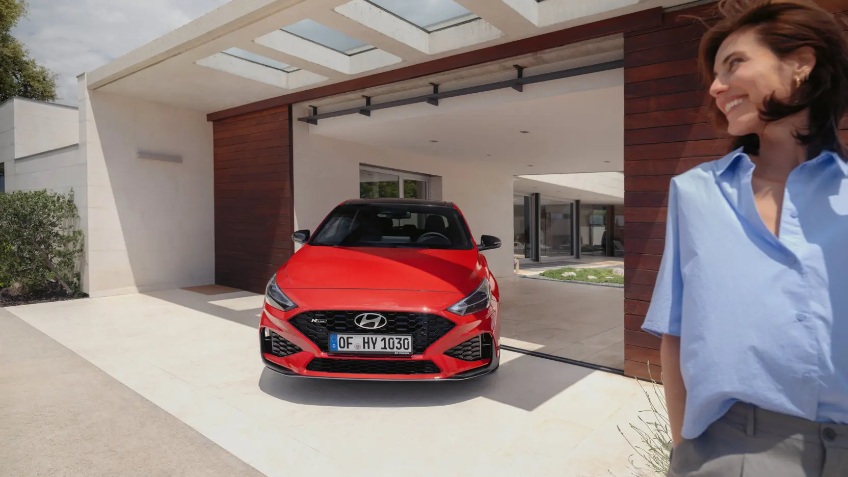 hyundai i30 n line frau steht neben auto und einem haus